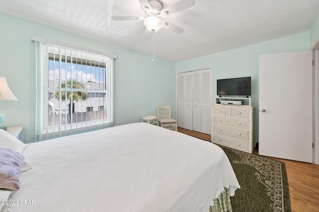 bedroom featuring ceiling fan, a textured ceiling, a closet, and wood-type flooring