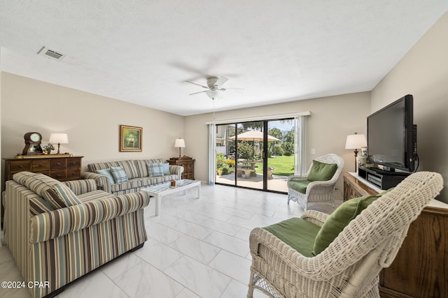 living room featuring ceiling fan and a textured ceiling