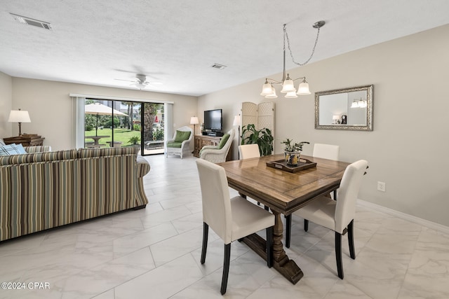 dining space with ceiling fan with notable chandelier and a textured ceiling