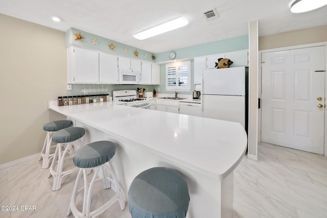 kitchen with sink, white cabinetry, kitchen peninsula, a kitchen breakfast bar, and white appliances