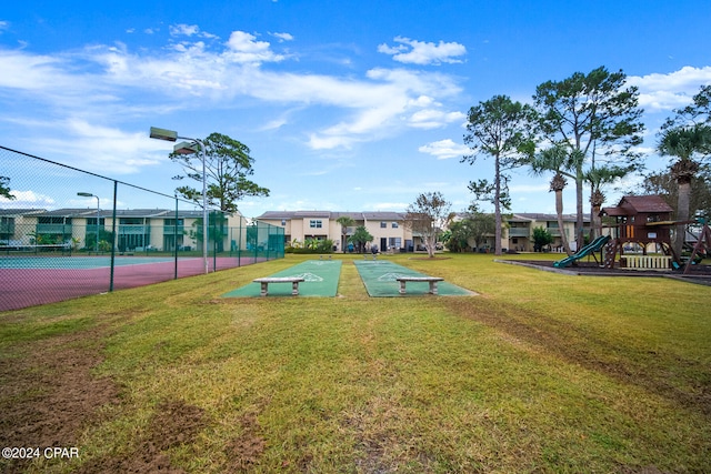 surrounding community featuring a lawn, tennis court, and a playground