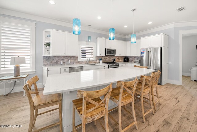 kitchen with tasteful backsplash, stainless steel appliances, sink, white cabinets, and light hardwood / wood-style floors