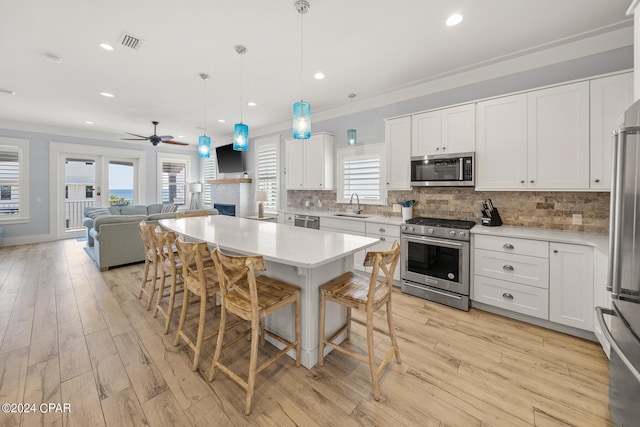 kitchen featuring light wood-type flooring, appliances with stainless steel finishes, white cabinetry, and plenty of natural light