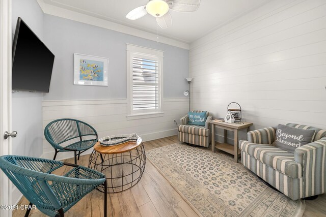 living area featuring crown molding, ceiling fan, and light hardwood / wood-style floors