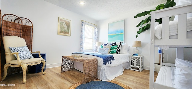 bedroom featuring a textured ceiling and light hardwood / wood-style flooring