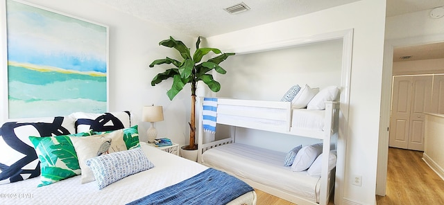 bedroom with a textured ceiling and light hardwood / wood-style floors