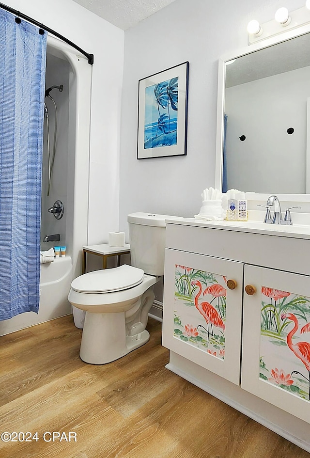 full bathroom with vanity, shower / bath combination with curtain, hardwood / wood-style flooring, and toilet