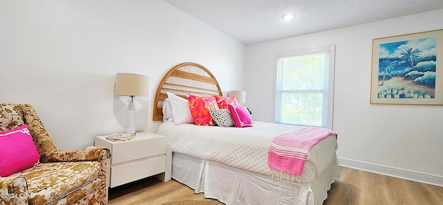 bedroom with light hardwood / wood-style flooring and a textured ceiling