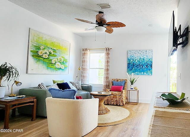 living room with a textured ceiling, hardwood / wood-style floors, and ceiling fan