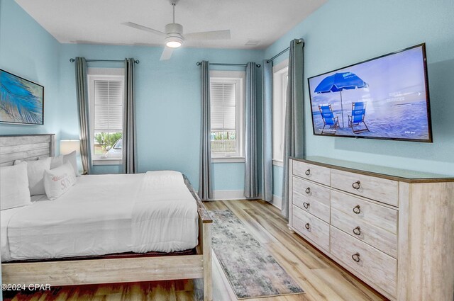 bedroom with ceiling fan, light wood-type flooring, and multiple windows