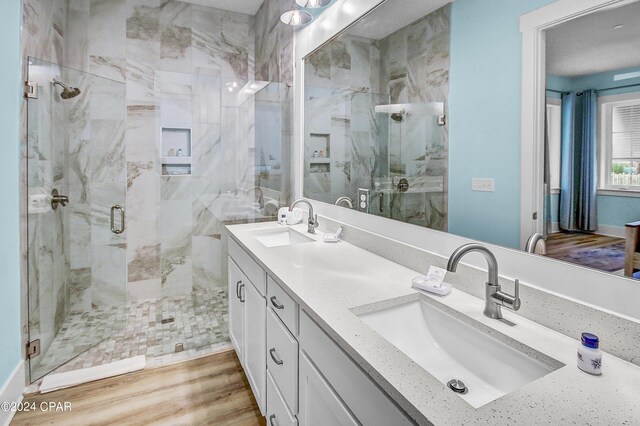 bathroom with double sink vanity, an enclosed shower, and hardwood / wood-style flooring