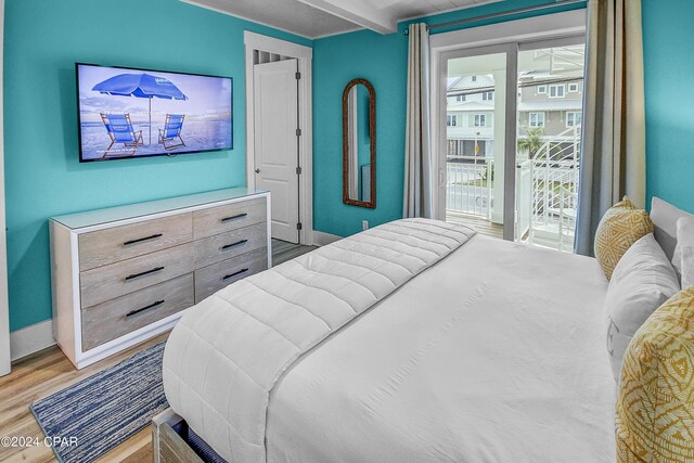 bedroom featuring access to exterior, beam ceiling, and light hardwood / wood-style floors