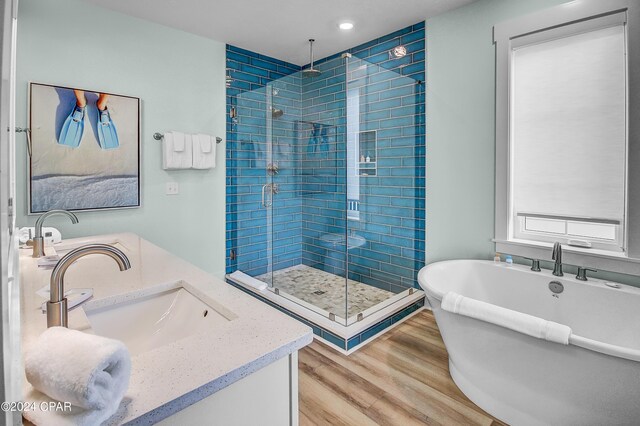 bathroom featuring shower with separate bathtub, dual bowl vanity, and hardwood / wood-style floors