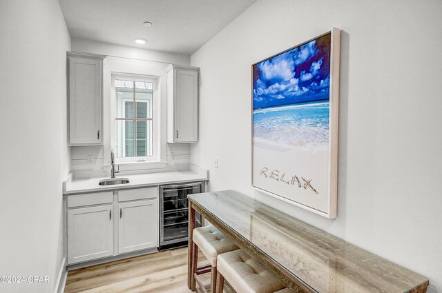 kitchen with sink, beverage cooler, and light hardwood / wood-style floors