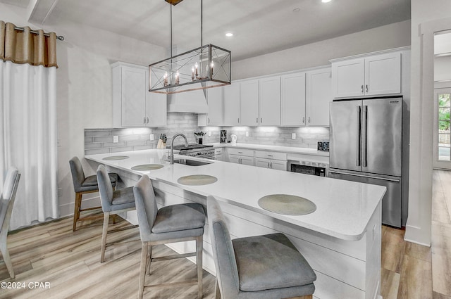 kitchen featuring backsplash, light wood-type flooring, high end appliances, and sink