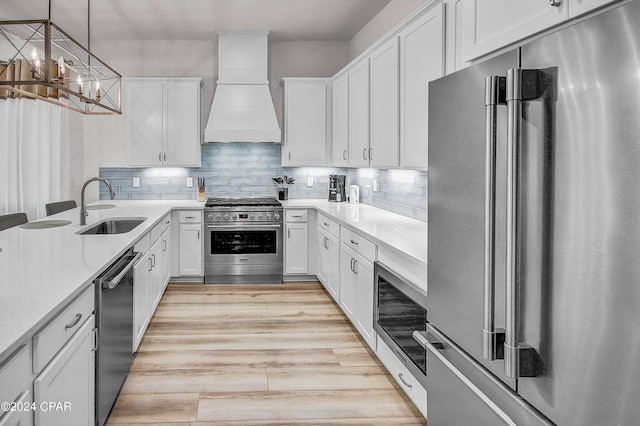 kitchen featuring decorative backsplash, custom exhaust hood, light wood-type flooring, sink, and high end appliances