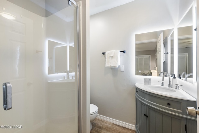 bathroom with hardwood / wood-style floors, vanity, toilet, and a shower with door