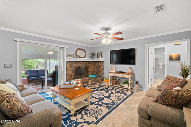 living room featuring ceiling fan, a stone fireplace, and crown molding