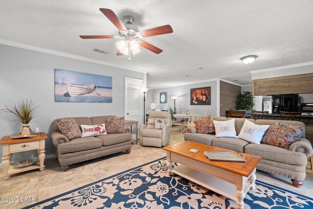 living room featuring ceiling fan, ornamental molding, and a textured ceiling