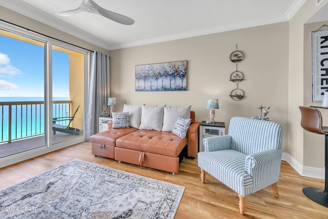 living room featuring crown molding, light hardwood / wood-style flooring, ceiling fan, and a water view