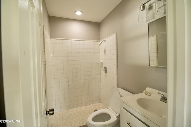 bathroom with vanity, toilet, and a tile shower