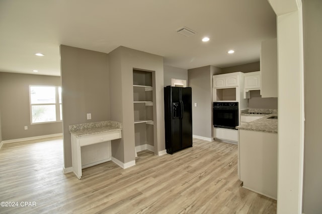 kitchen featuring white cabinetry, light stone countertops, light hardwood / wood-style floors, and black appliances