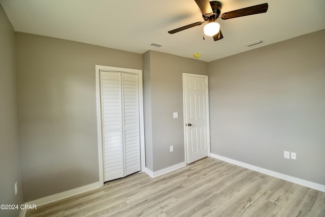 unfurnished bedroom featuring light hardwood / wood-style floors, a closet, and ceiling fan