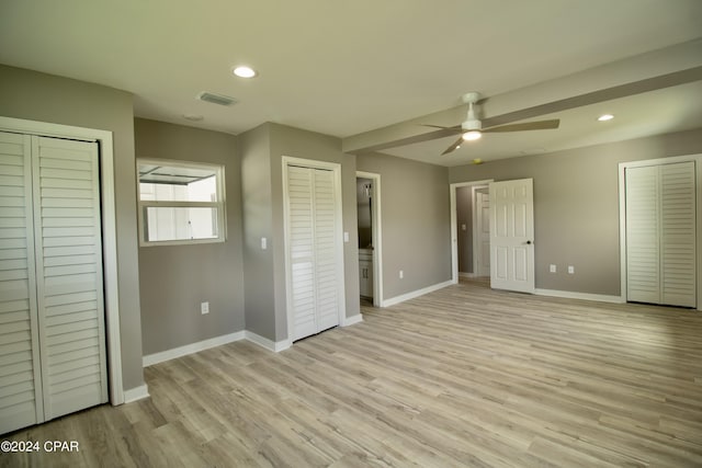 unfurnished bedroom featuring ceiling fan, light hardwood / wood-style flooring, and multiple closets