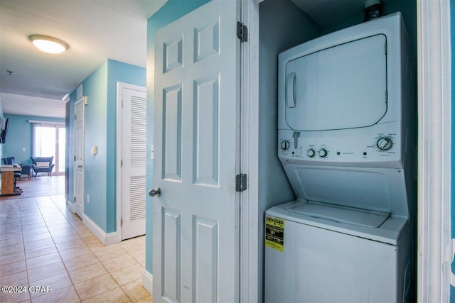 laundry area featuring stacked washing maching and dryer and light tile patterned flooring