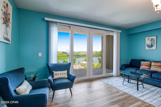 living area with a water view, french doors, and light hardwood / wood-style floors