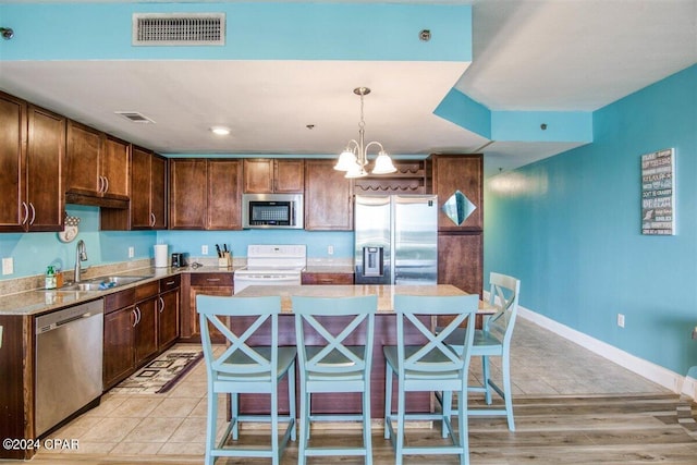 kitchen with pendant lighting, stainless steel appliances, a breakfast bar, and sink