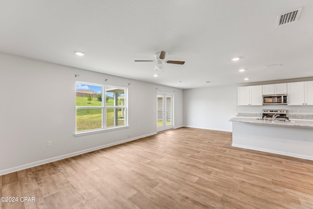 unfurnished living room with light hardwood / wood-style floors, sink, and ceiling fan