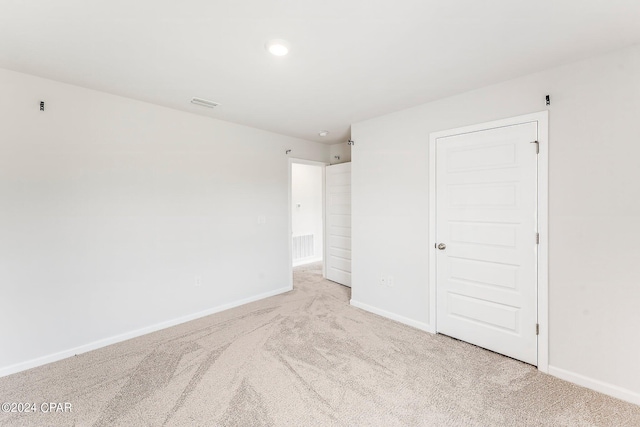 unfurnished bedroom with light carpet and a closet