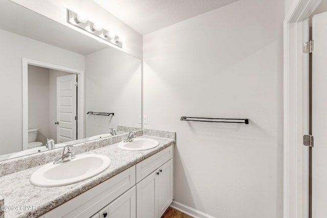 bathroom featuring toilet and double sink vanity