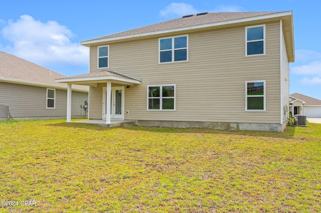 rear view of property with a patio, cooling unit, and a lawn