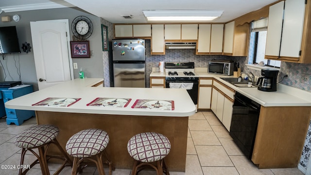 kitchen with light tile patterned flooring, cream cabinets, stainless steel appliances, decorative backsplash, and sink