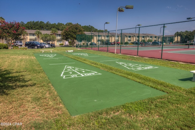 surrounding community featuring tennis court and a yard