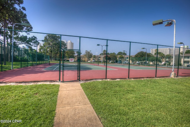 view of tennis court with a lawn and basketball hoop