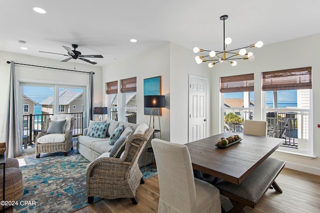 dining room with hardwood / wood-style floors, ceiling fan with notable chandelier, and plenty of natural light