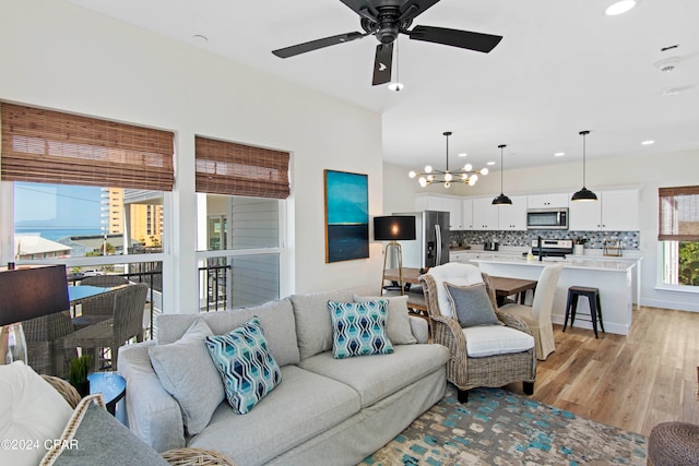 living room featuring light hardwood / wood-style floors and ceiling fan with notable chandelier