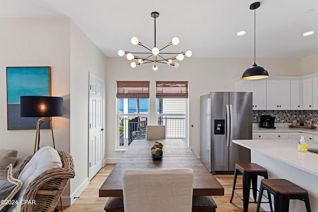 dining area with light hardwood / wood-style flooring and an inviting chandelier