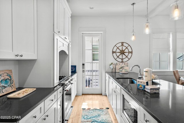 kitchen with sink, hanging light fixtures, light hardwood / wood-style floors, white cabinets, and a breakfast bar area