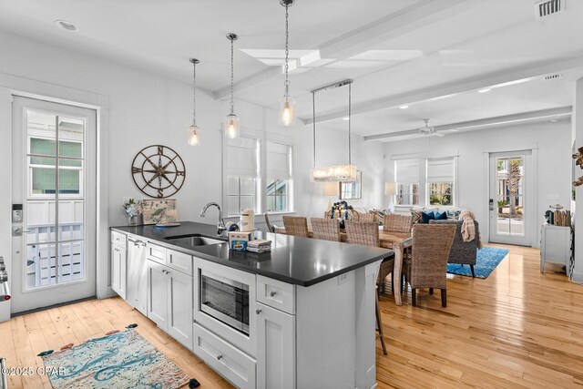 kitchen featuring white cabinetry, light hardwood / wood-style floors, sink, and an island with sink