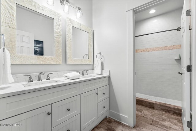 bathroom featuring vanity, a tile shower, and hardwood / wood-style flooring