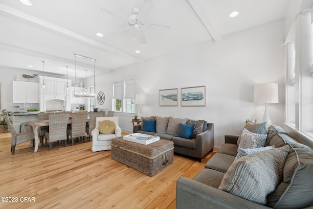 living room with beamed ceiling, light wood-type flooring, and ceiling fan