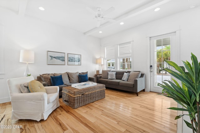 living room with beam ceiling, light wood-type flooring, and ceiling fan