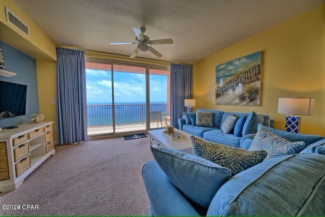 carpeted living room with ceiling fan, a textured ceiling, and a water view