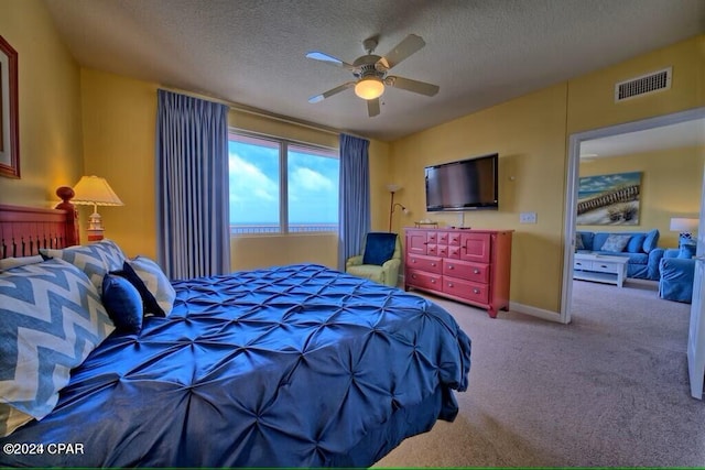 carpeted bedroom with ceiling fan and a textured ceiling