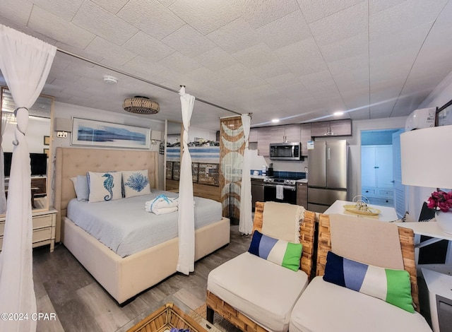 bedroom with stainless steel refrigerator and wood-type flooring