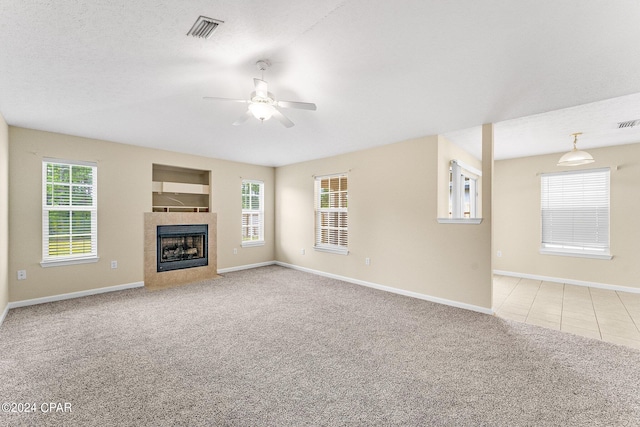 unfurnished living room featuring light carpet, a tile fireplace, and a healthy amount of sunlight